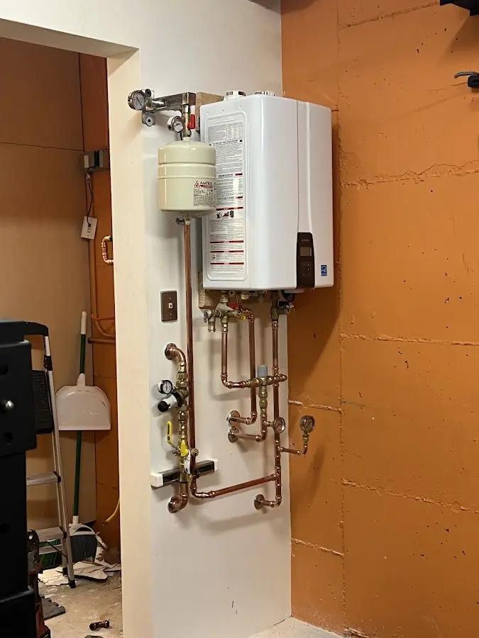 Plumbing technician inspecting water heater connections in Whetstone